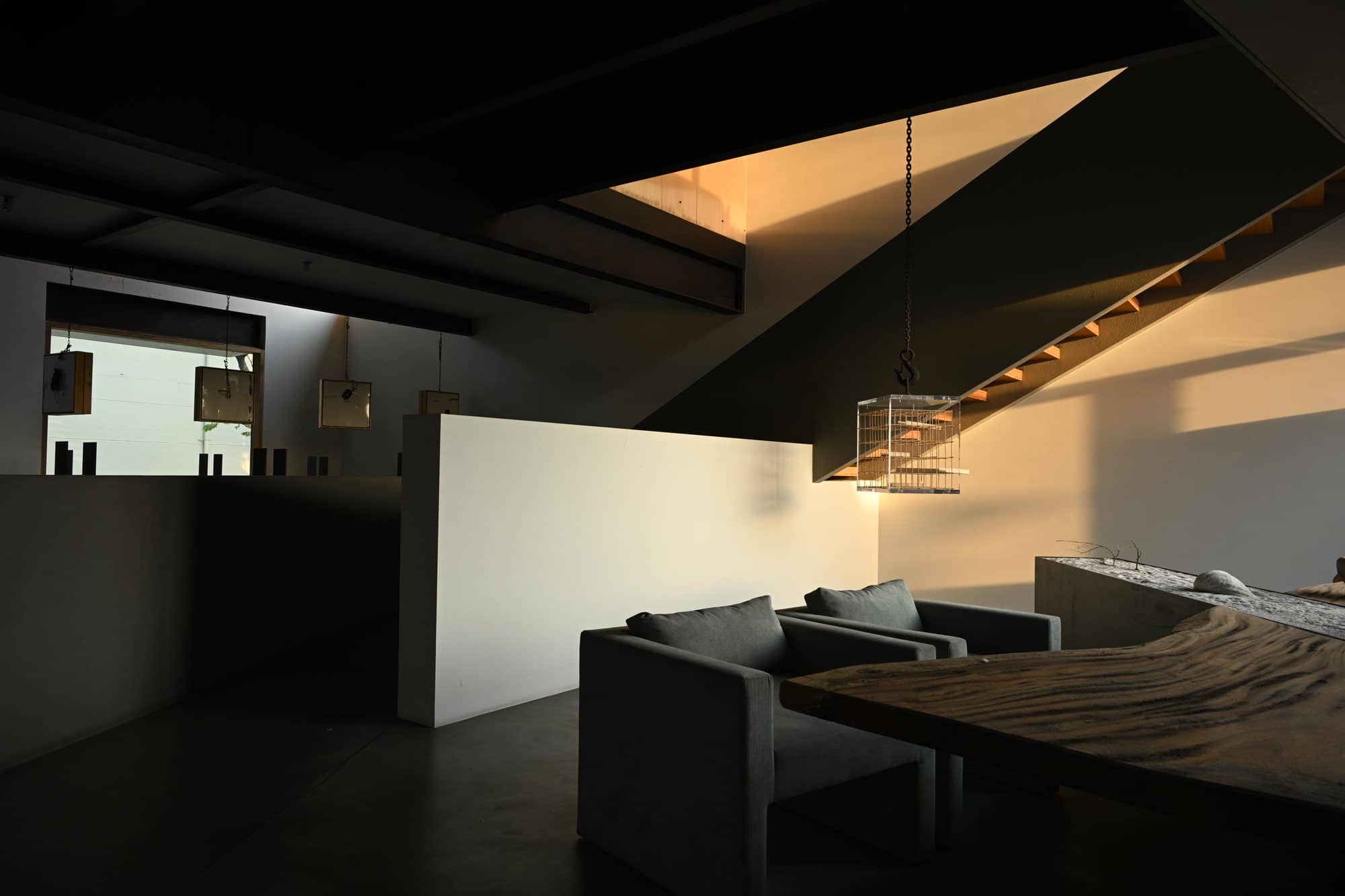 Sloped-beam lounge with white partition and low seating — after dark
