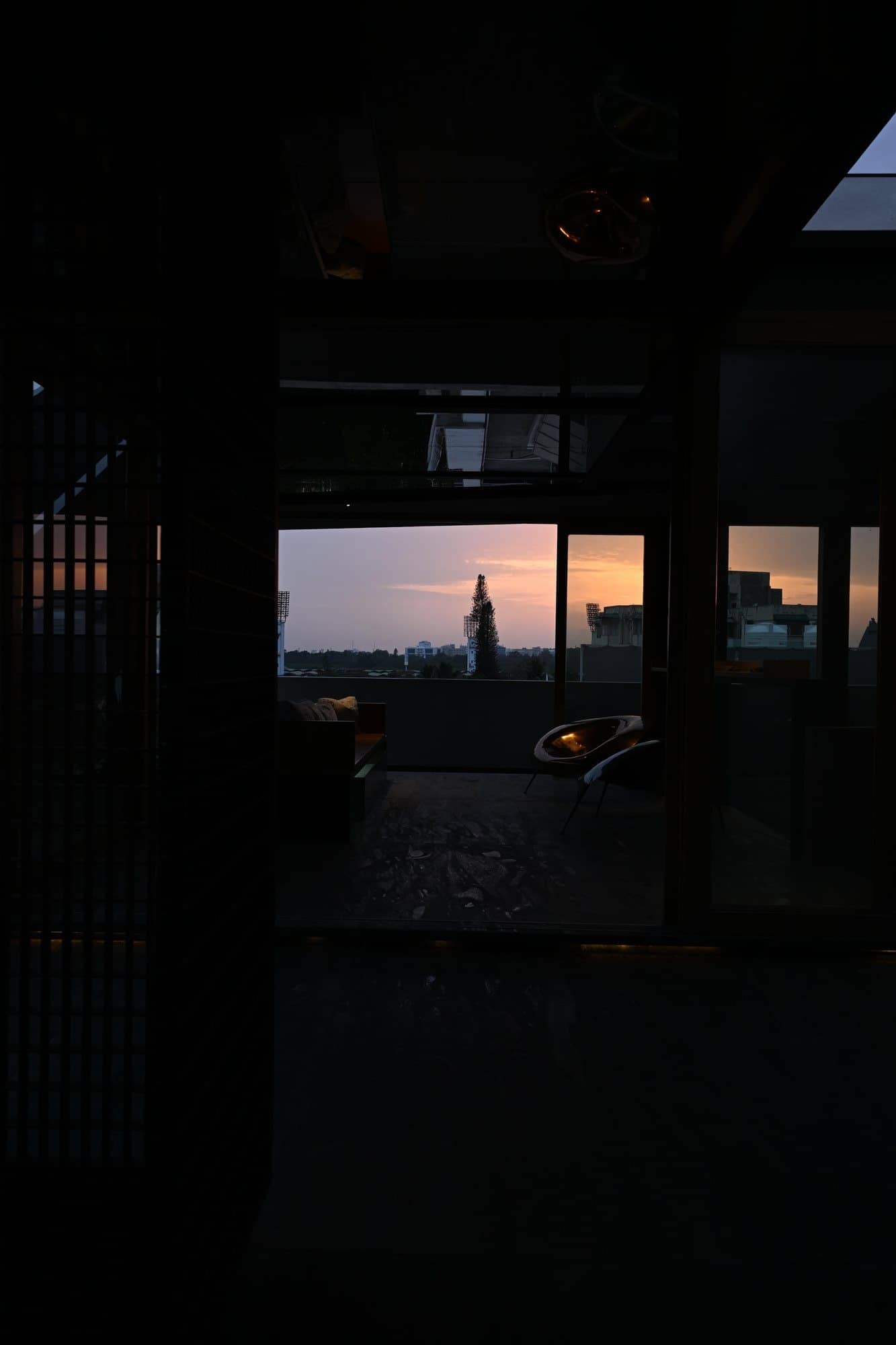 Glass-roof void with layered steel framing and stone — after dark