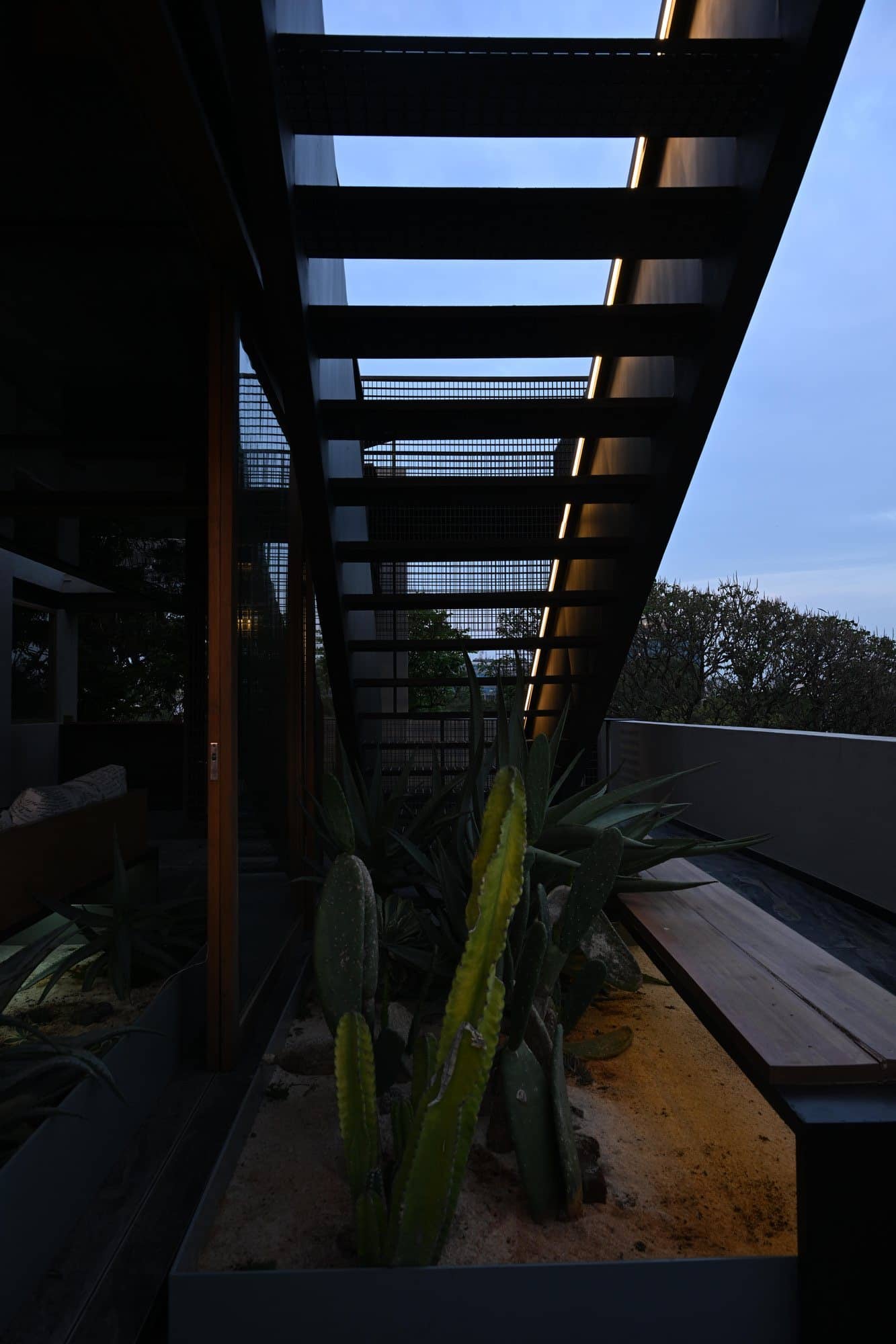 Looking up the planted stairwell void with steel railings — after dark