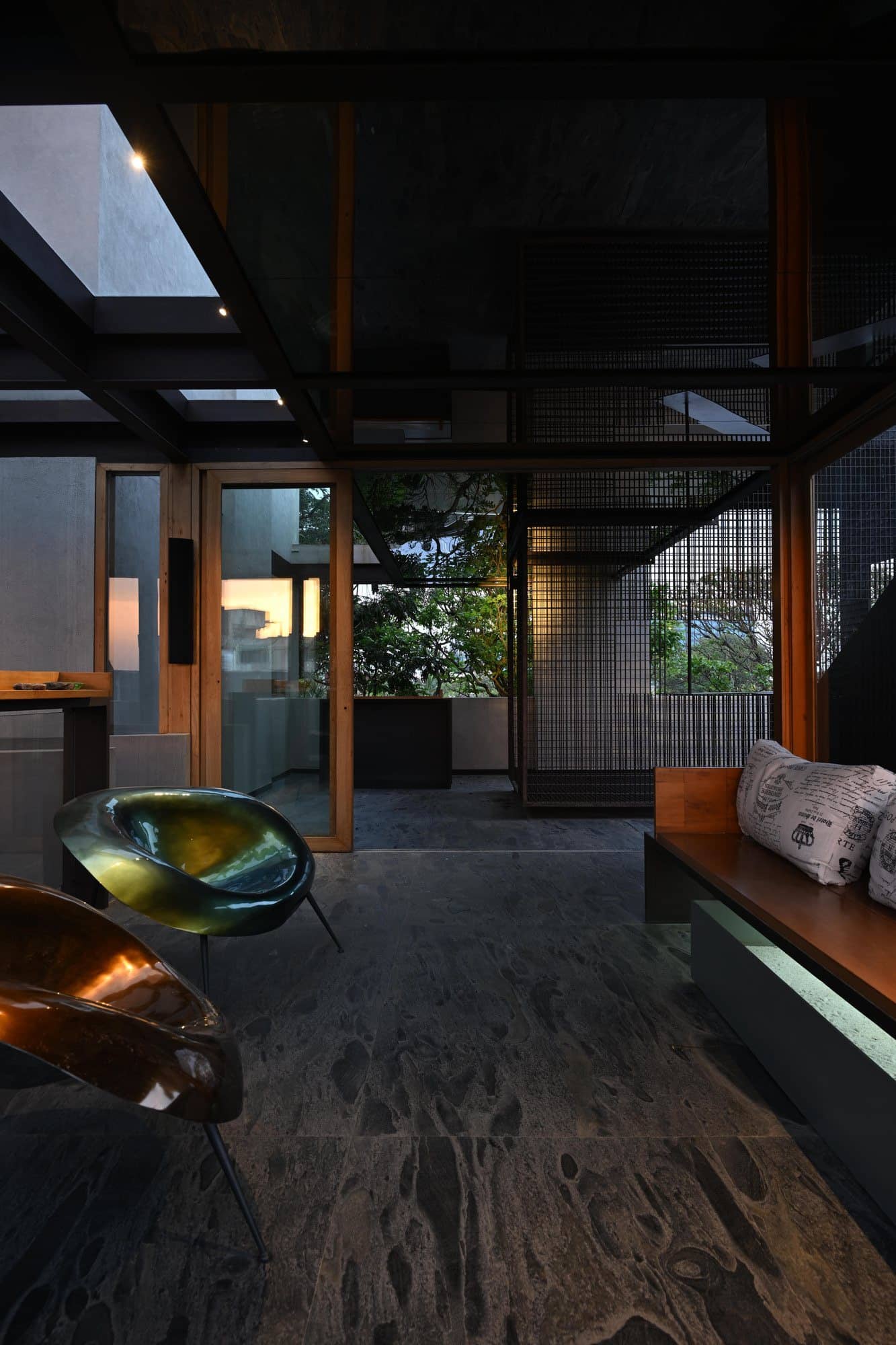 Stone wall passage with suspended brass detail and greenery — after dark