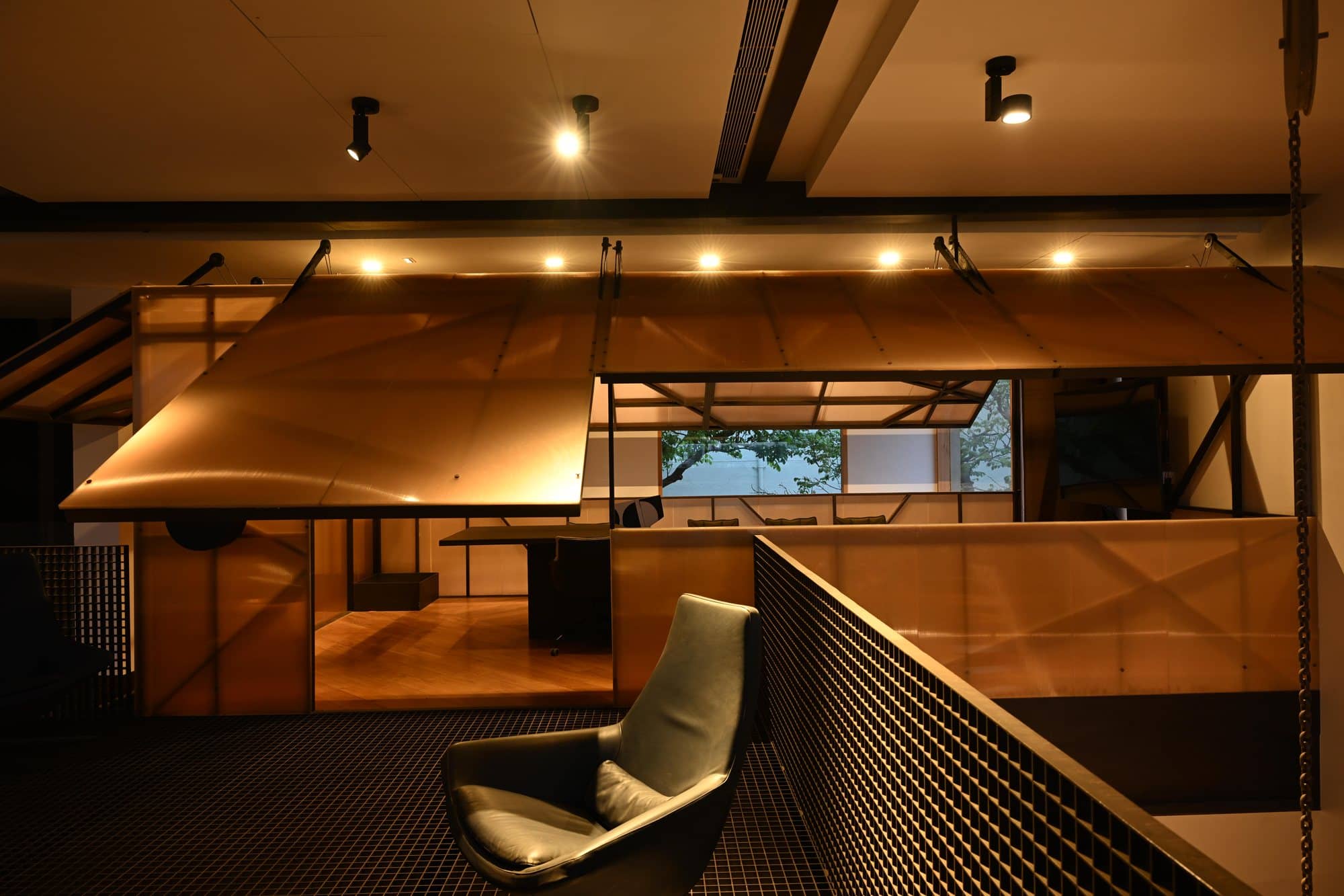 Curved timber canopy loft with sculptural seating — after dark