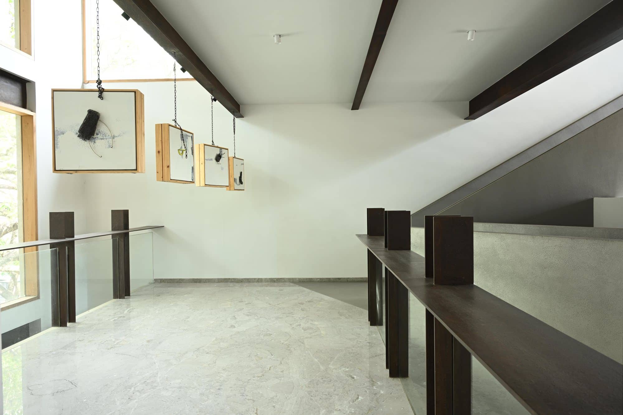 Sloped-ceiling gallery landing with framed works and railing — daylight