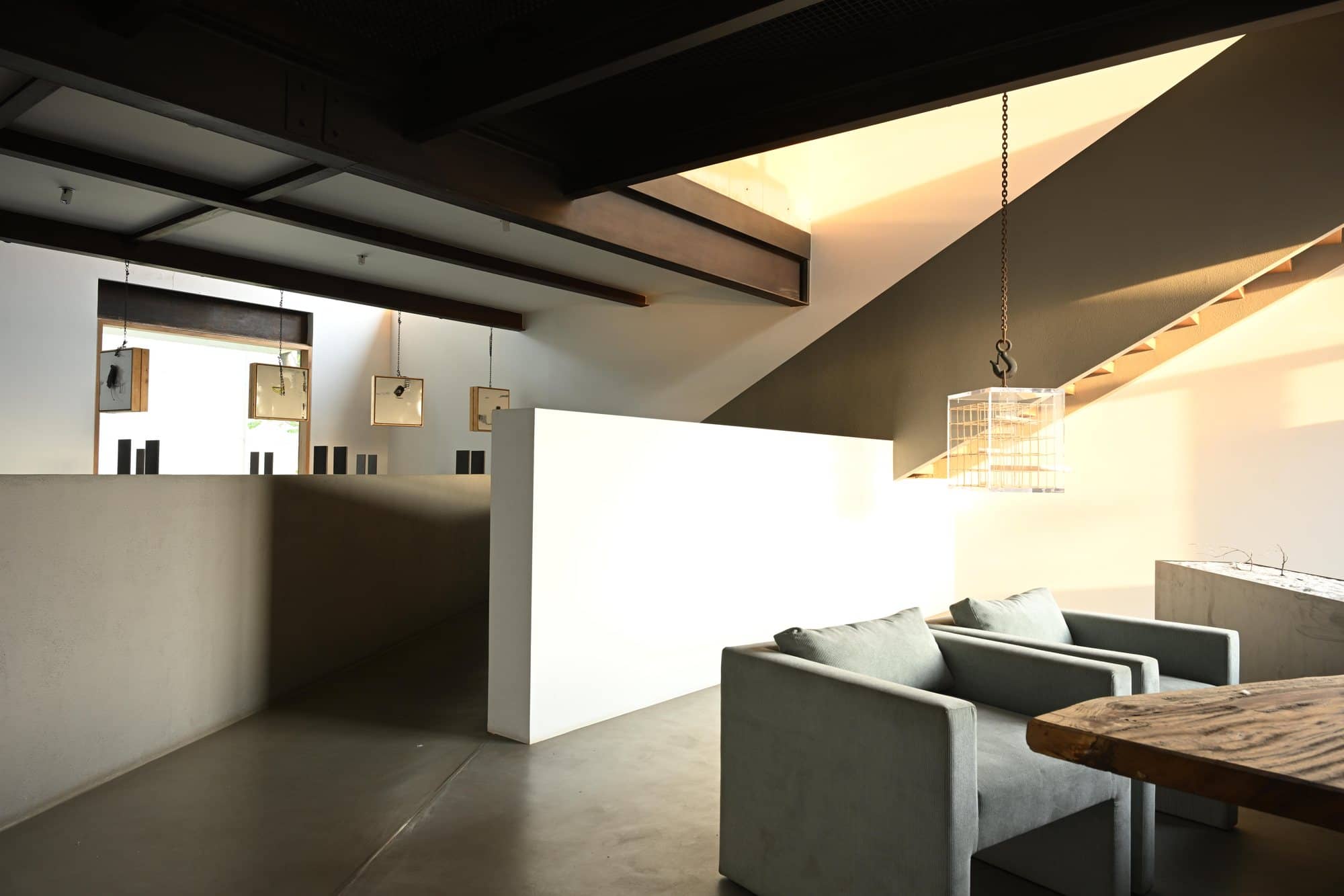 Sloped-beam lounge with white partition and low seating — daylight