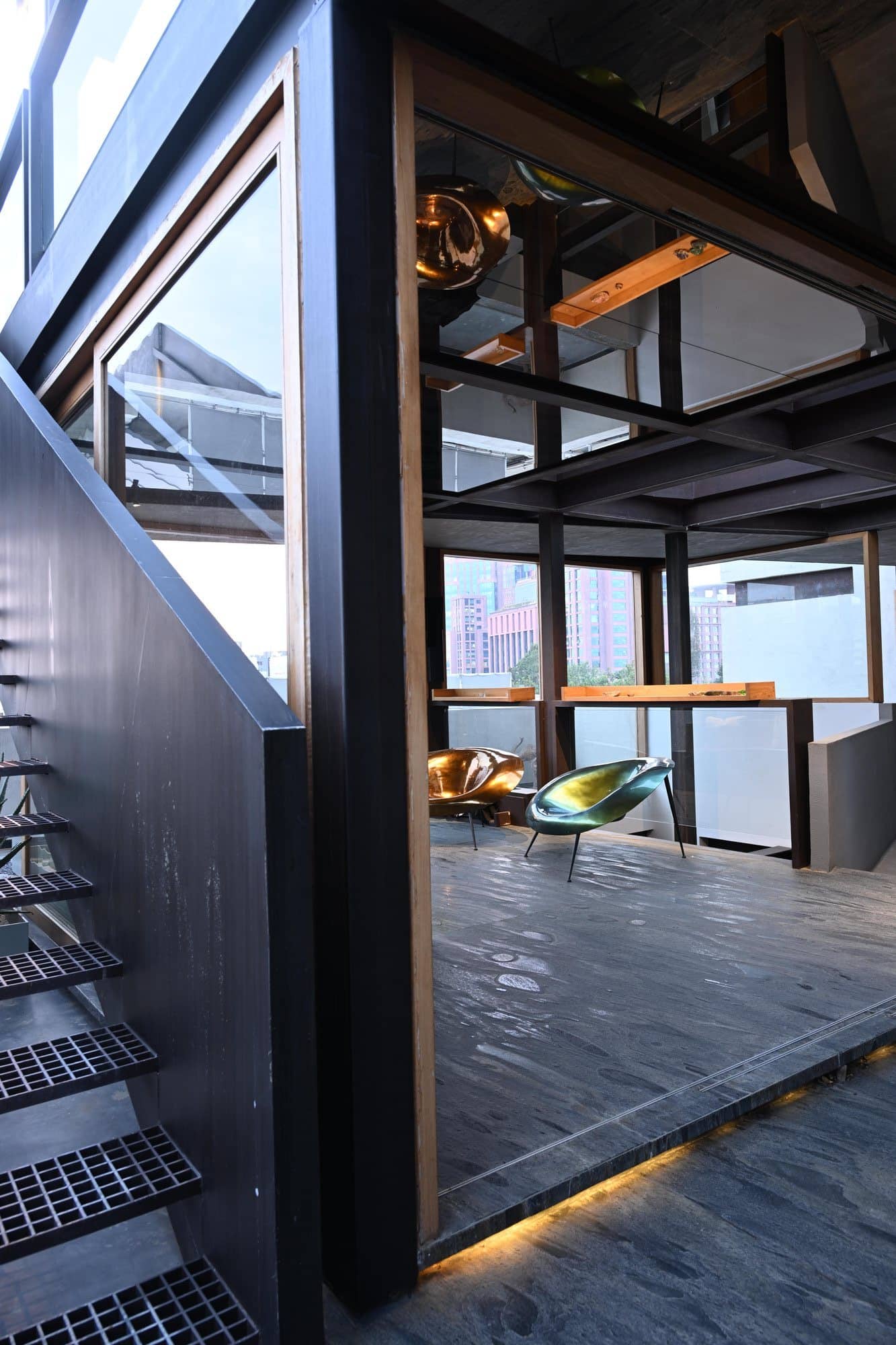Glass-roof void with layered steel framing and stone — daylight