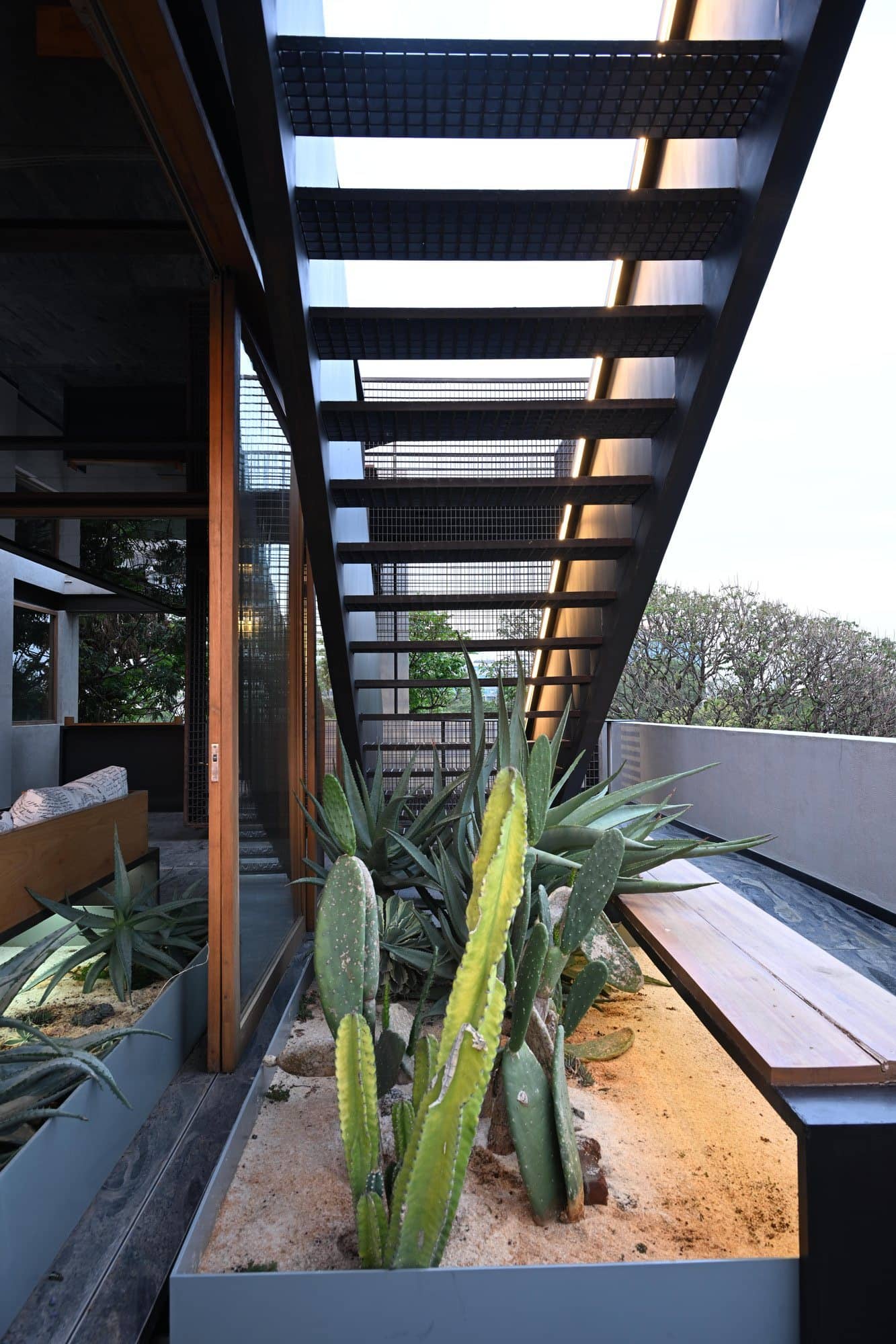 Looking up the planted stairwell void with steel railings — daylight